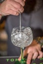 View of bartender preparing glass of tonic gin in flask with lots of ice in bar of drinks