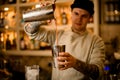 View on bartender who pours tomato juice from one steel shaker glass into another glass Royalty Free Stock Photo