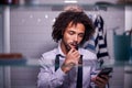 View Through Bathroom Cabinet Of Businessman Brushing Teeth And Checking Phone Before Going To Work Royalty Free Stock Photo