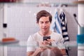 View Through Bathroom Cabinet Of Man Checking Messages On Phone Before Going To Work Royalty Free Stock Photo