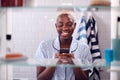 View Through Bathroom Cabinet Of Woman Checking Messages On Phone Before Going To Work Royalty Free Stock Photo