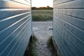 View between beach huts onto marshlands with summer sun setting