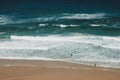 View of beach with large waves near Atlantic coast. Surfers on the ocean coast with surfboard. Praia Grande, Sintra, Portugal. Act