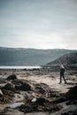 View of a beach in norwegian fjord with young blodne woman walking in the front of the photo