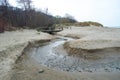 View of a beach washed by sea water, with rocks. Wet sand is drawings rivers and stones under a dramatic cloudy sky Royalty Free Stock Photo