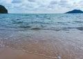 View of the beach and waves with the backdrop of the island and the clouds.