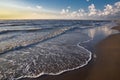 View from the beach on the white foam cups of the rising waves at high tide in the North Sea, all this at sunset Royalty Free Stock Photo