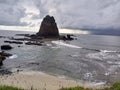 the view of a beach with white sand, small waves and surrounded by beautiful rocky hills