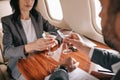 View of bearded businessman and businesswoman toasting martini glasses in private jet