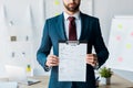 View of bearded recruiter in suit standing and holding clipboard with resume letters