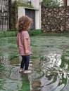 View of beautiful barefoot girl playing in puddle after rain Royalty Free Stock Photo
