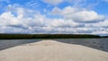 View of the beautiful breakwater that goes into the distance. Green landscape intersected with blue sky.