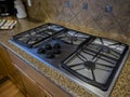 view of a beautiful gas stove top with black knobs against a square tiled backsplash Royalty Free Stock Photo