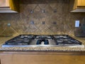 view of a beautiful gas stove top with black knobs against a square tiled backsplash Royalty Free Stock Photo