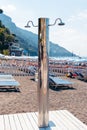 View of a beautiful, new, beach shower on the beach. Mountains in the background. Vertical photo. Glossy stainless steel products Royalty Free Stock Photo