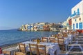 359/5000 Myconos Greece View of a beautiful terrace with wicker traditional chairs and white tablecloths directly on the sea, On t