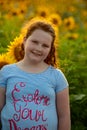 Beauty joyful young girl with sunflower enjoying nature and laughing on summer sunflower field. Sunflare, sunbeams, glow Royalty Free Stock Photo