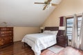 View of a bedroom with a wooden floor and chest of drawers, a ceiling fan and windows.