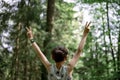 View from behind of a boy in his eary teens standing with his arms raised high in victorious gesture