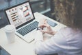 View from behind,close-up of businesswoman sitting at desk in office and synchronizes smart watch with laptop. Royalty Free Stock Photo