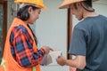View from behind of a female constructor with pointing finger showing paint examples to a builder
