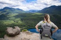 View from behind of a female hiker standing on the top of a mountain overlooking a beautiful scenic rocky mountain landscape and a Royalty Free Stock Photo