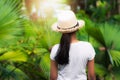 View from behind a girl wearing straw hat standing in the palm garden under sunlight Royalty Free Stock Photo