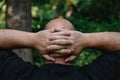 View from behind of mature man with little hair or alopecia with his hands on the nape of his neck.