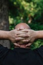 View from behind of mature man with little hair or alopecia with his hands on the nape of his neck.