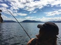 A view from behind of a young beautiful woman holding a fishing rod fishing in the ocean on a small boat in the gulf islands Royalty Free Stock Photo