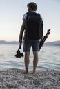 View from behind of a young professional photographer with a tripod and gimbal camera holder in his hands Royalty Free Stock Photo