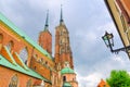 Cathedral of St. John the Baptist catholic church with two brick towers with spire and street lamp on building in old historical c Royalty Free Stock Photo