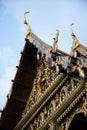 View from below from the details of a Thai Temple roof with blue sky in the background