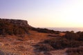 View from below on the red stony soil and Cape Cavo Greco Capo Greco in the sunset. Cyprus