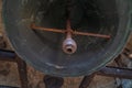 View from below of a restored ancient bronze clapper bell with a somewhat cracked greenish tone from the Clerecia church in