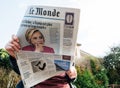 View from below of woman reading latest newspaper Le Monde with portrait of Hillary Clinton
