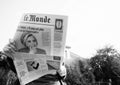 View from below of woman reading latest newspaper Le Monde with portrait of Hillary Clinton