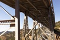 View Beneath Metal Construction Of Bridge Supports Against Blue Sky And Rocks. Rivets And