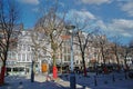 View beyond bare trees on square with historical buildings, exterior cafes and restaurants