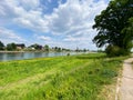 View beyond cycling track over green agricultural field on river Maas, village Kessel background - Netherlands