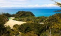 View beyond tree branches on bay with white sandbank turquoise water, green hills and blue ocean background Royalty Free Stock Photo