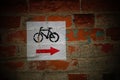 View of a bicycle sign with a red direction arrow over an old brick wall Royalty Free Stock Photo