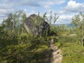 View on big rock stone next footpath of Kungsleden hiking trail with birch trees and lake in background. Summer day Royalty Free Stock Photo