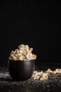 View of black bowl with popcorn on dark table with salt , selective focus, black background