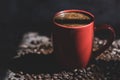 View of a black coffee in a red cup among the delicious coffee beans
