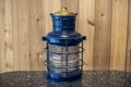 A black and copper vintage nautical boat lantern on top of a marble table, against a wooden wall background Royalty Free Stock Photo