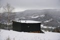 View of Black wooden tiny cabin with view on snowy pine forests in Ukraine