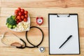 View of blank clipboard with pen near stethoscope, alarm clock and tasty vegetables on heart-shape plate Royalty Free Stock Photo