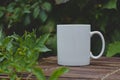 A blank white coffee mug on the wooden table in the garden Royalty Free Stock Photo