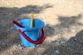 Blue bucket with the red hilt laying on the beach
